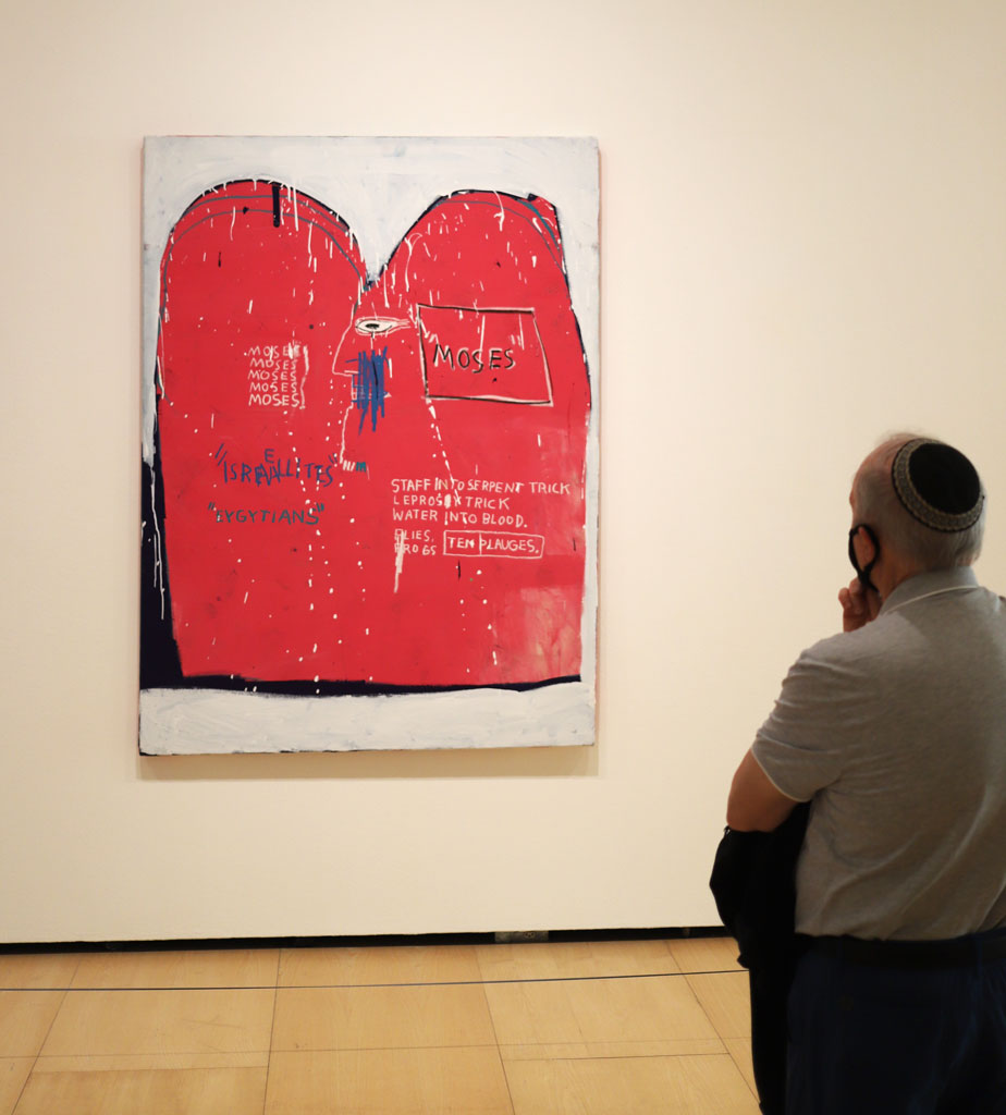 A galllery visitor checks out a Basquiat painting